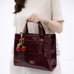 COACH SIGNATURE MAROON PATENT MINI TOTE BAG WITH CHERRY CHARM